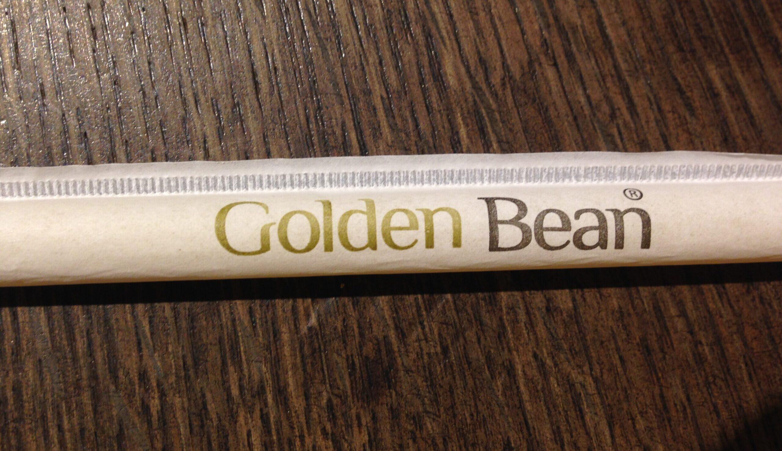 Papiertrinkhalm mit Golden-Bean-Logodruck auf Holz